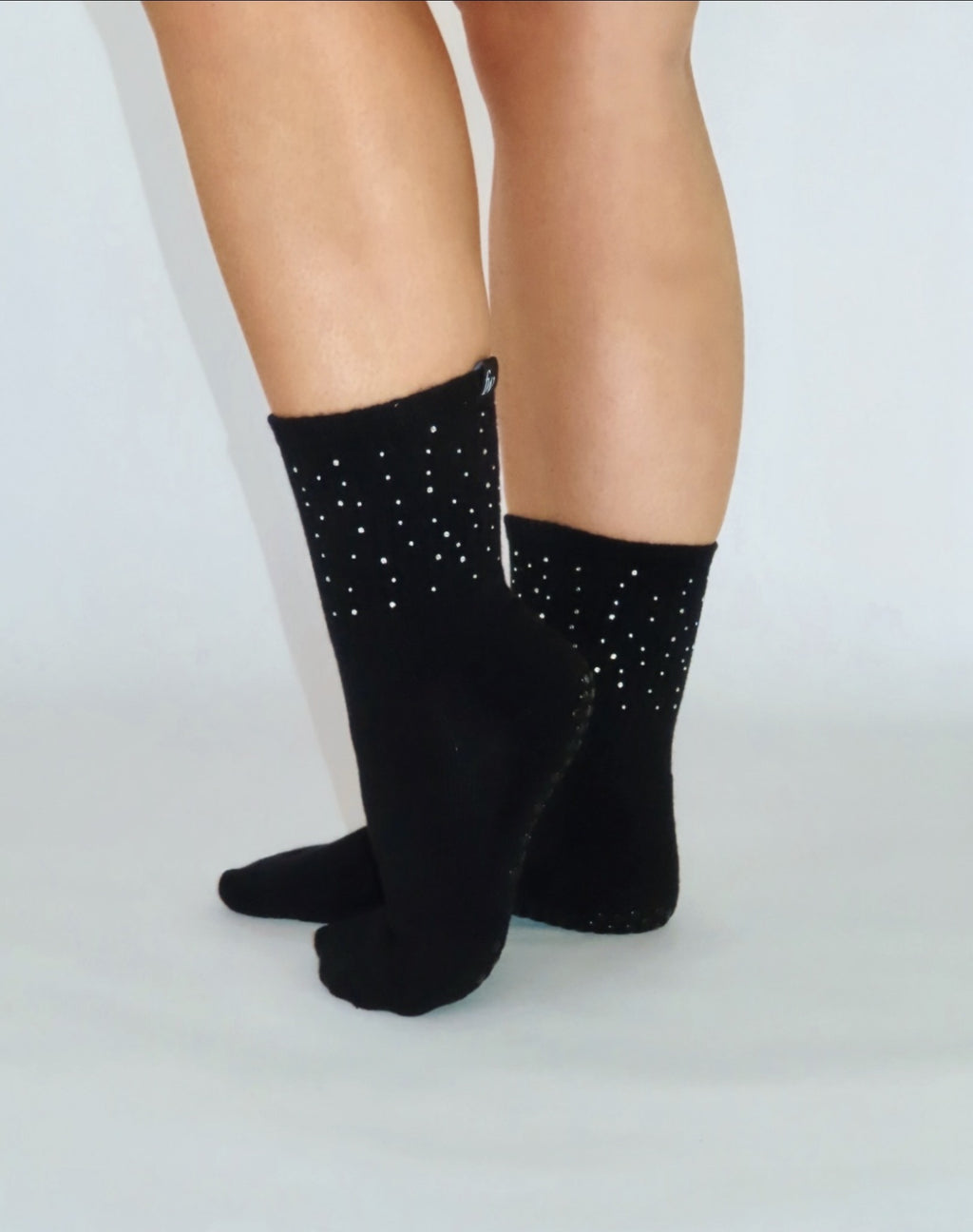 Rhinestone black grip socks on feet, standing